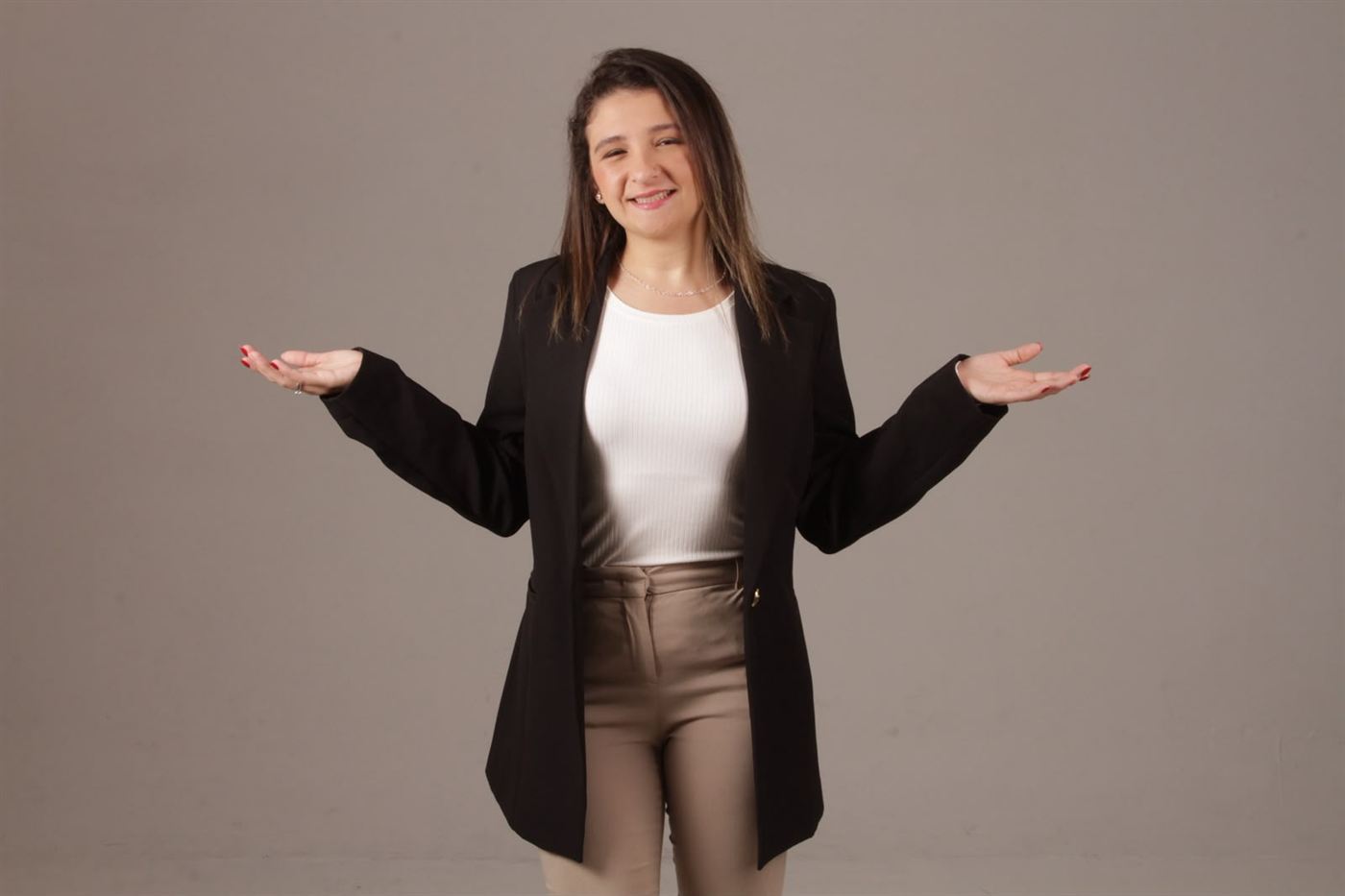 Bruna Fernandes de blazer preto, sorrindo com os braços abertos